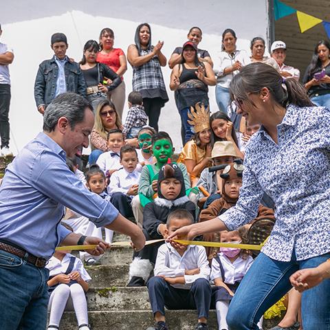 Adultos entregan plantas a niños y niñas durante una actividad de siembra.