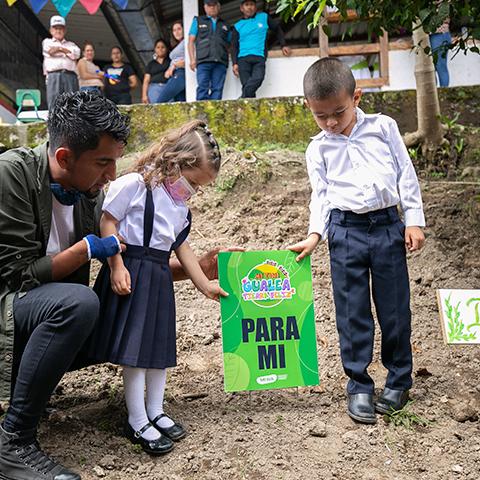 Adultos acompañan a estudiantes en la presentación de un cartel sobre el cuidado del ambiente.