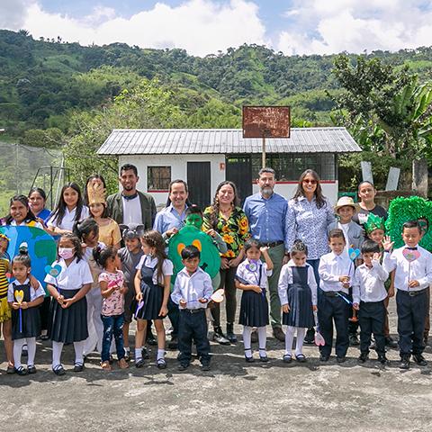 Niños, niñas y adultos posan juntos frente a una escuela durante la entrega del espacio TINI.