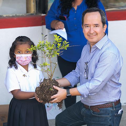 Leopoldo Báez y estudiante sosteniendo una planta en sus manos.