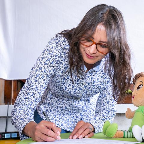 Mujer firma un documento relacionado con la actividad TINI.
