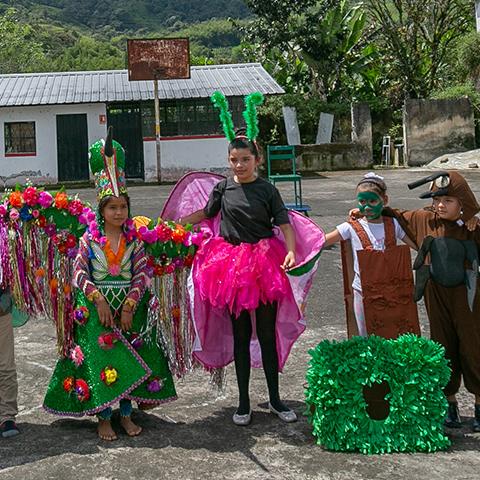 Niños y adultos participan en una actividad cultural con trajes tradicionales y decoraciones coloridas.