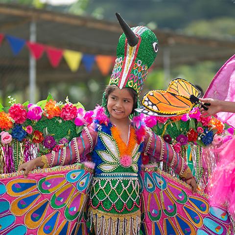Niña con traje tradicional y elementos coloridos participa en una celebración escolar.