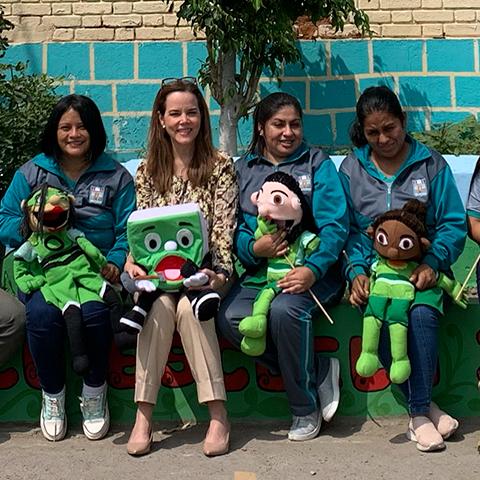 Mujeres y estudiantes posan con personajes y materiales educativos sobre el cuidado ambiental.