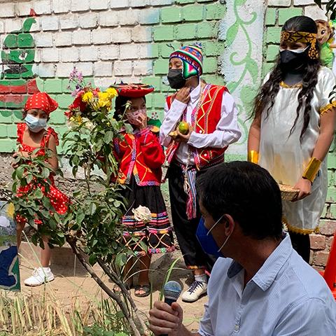 Niños y adultos participan junto a plantas y carteles sobre el cuidado del ambiente.
