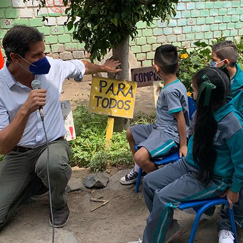 Niños y adultos participan junto a plantas y un cartel que dice Para Todos.