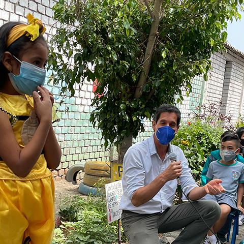 Niños y adultos participan junto a plantas y carteles sobre el cuidado del ambiente.