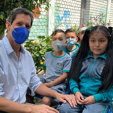 Adulto conversa con estudiantes durante una actividad educativa en la escuela
